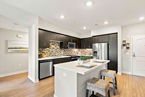 A kitchen with a white island and a fridge.