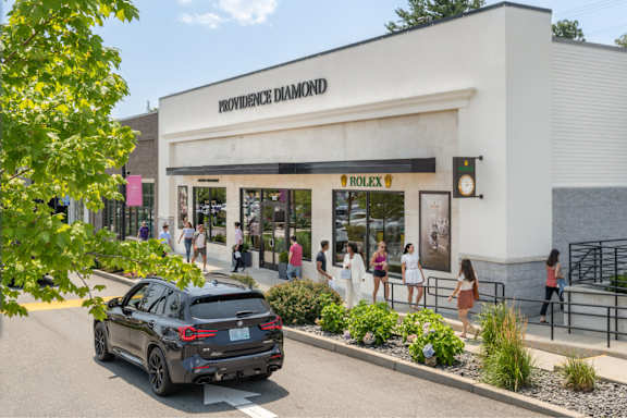 A black car is parked in front of a Providence Diamond store.