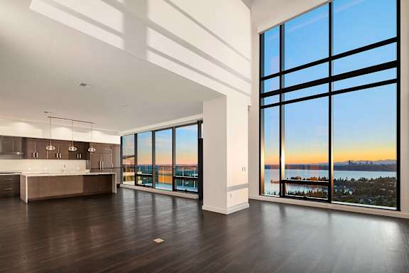 an open living room with a view of the water and a kitchen with large windows at Two Lincoln Tower Apartments, Bellevue, WA, 98004