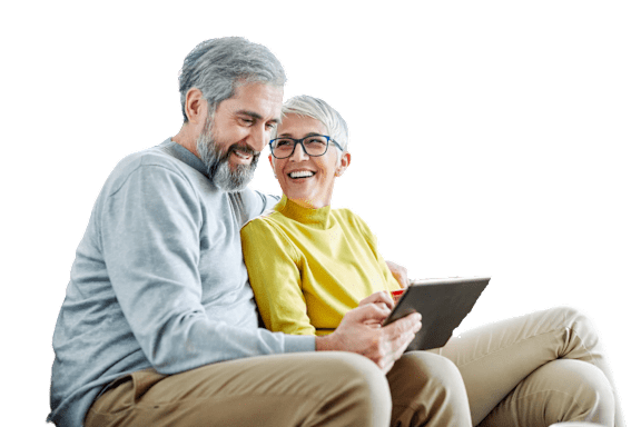 An older couple is sitting together and looking at a tablet.