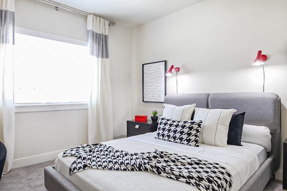 A bedroom with a bed covered in a black and white patterned comforter.