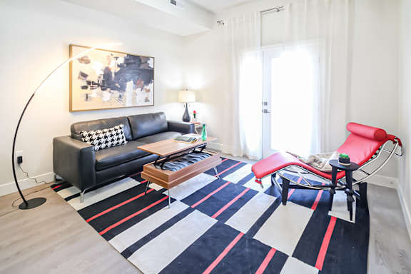 A black and white sofa with a red chair in front of a white door.