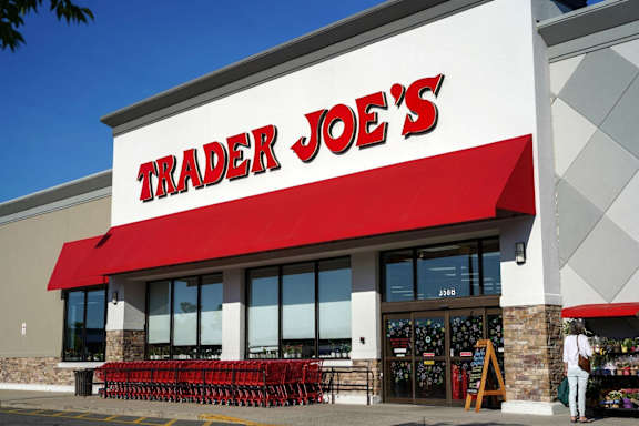 A Trader Joe's storefront with a red awning and a woman standing in front.