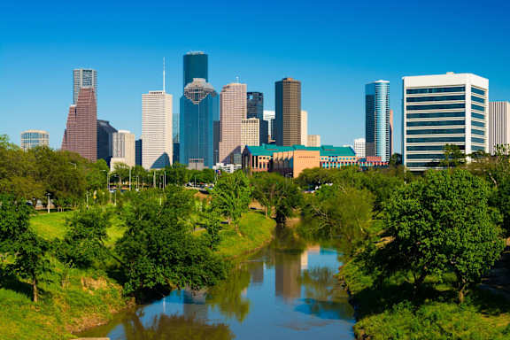 A city skyline with a river running through a park.
