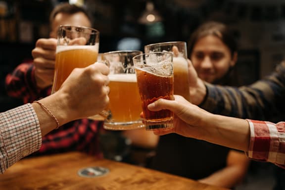 A group of people toasting with beer glasses in a bar.
