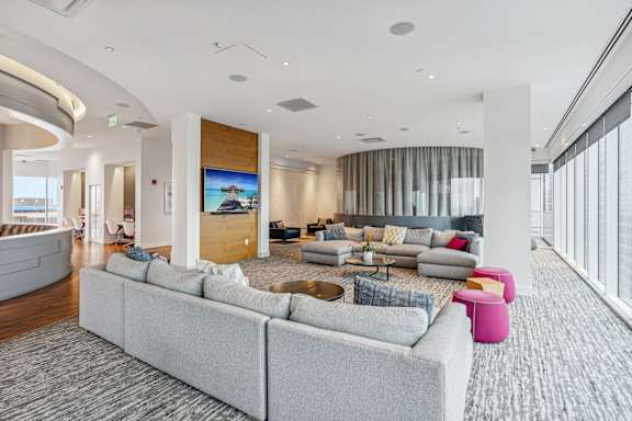 A modern living room with a grey sofa and a large screen on the wall.