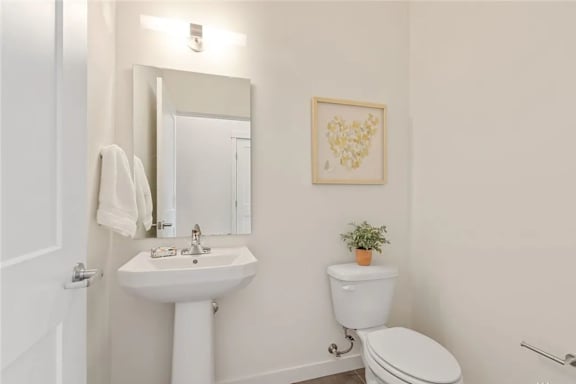 A white bathroom with a toilet, sink, and mirror.