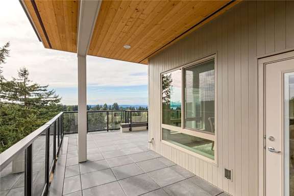 A balcony with a glass railing and a wooden ceiling.