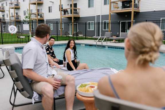a group of people sitting around a swimming pool
