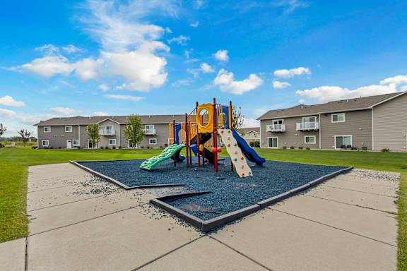 A playground with a slide and a green slide cover.