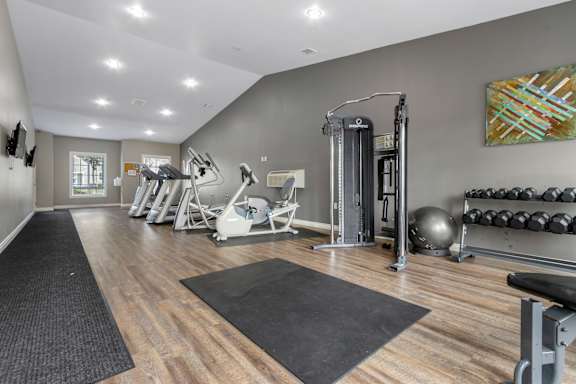 A gym with a variety of equipment including weights and a bench.