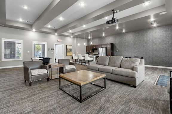 A spacious living room with a grey sofa, a wooden coffee table, and a television mounted on the wall.