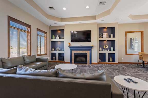 A living room with a grey couch and a fireplace.