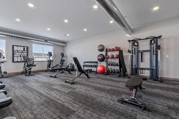A gym with a variety of equipment including a bench, weights, and a squat rack.