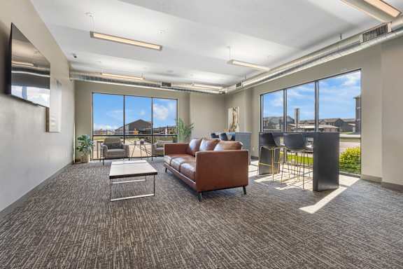 A spacious living room with a brown sofa and a grey coffee table.