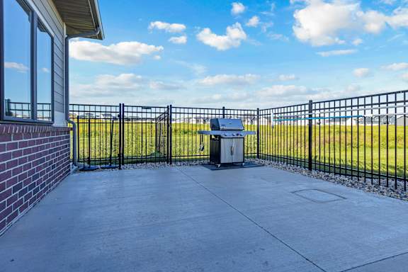 A black metal fence surrounds a concrete patio with a trash can in the middle.