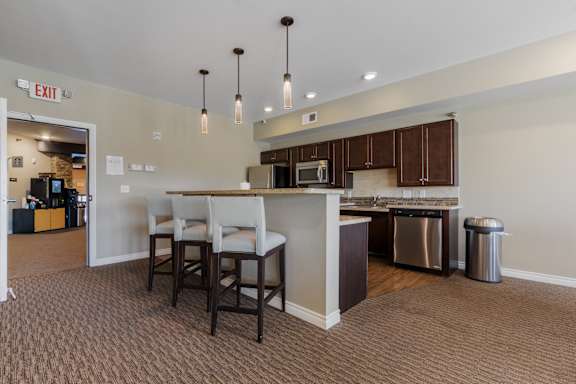 A kitchen area with a bar and chairs.