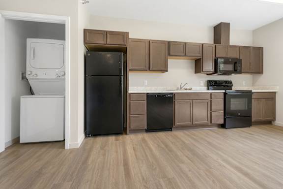 A kitchen with black appliances and brown cabinets.