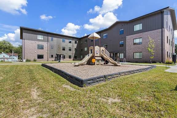 A playground area in front of a multi-story building.