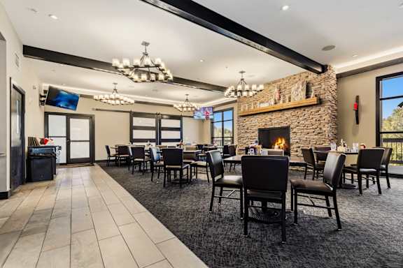 A modern dining room with a stone fireplace and a large table set for a meal.