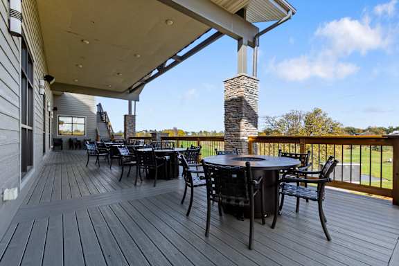 A wooden deck with a table and chairs and a stone chimney.