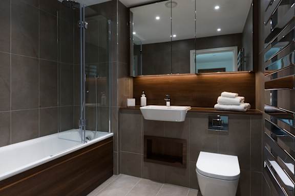 A modern bathroom with a white toilet, sink, and a glass shower stall.
