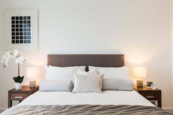 a bedroom with a large bed with white pillows and a brown headboard