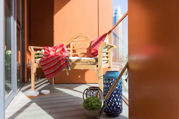 a balcony with a bench and two umbrellas on it