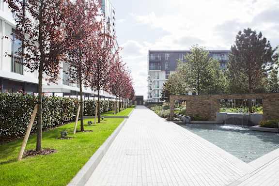 a walkway next to a canal with trees and buildings