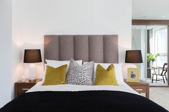 a bedroom with a bed with pillows and a brown headboard
