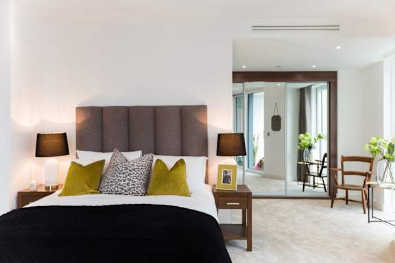 a bedroom with a bed and a view of a living room and a dining area