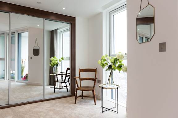 a living room with a mirror and a table with flowers