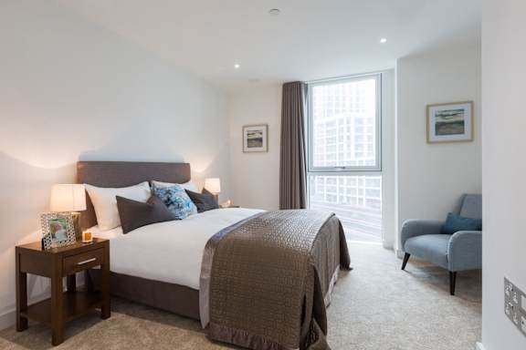 a bedroom with a bed and a chair and a window