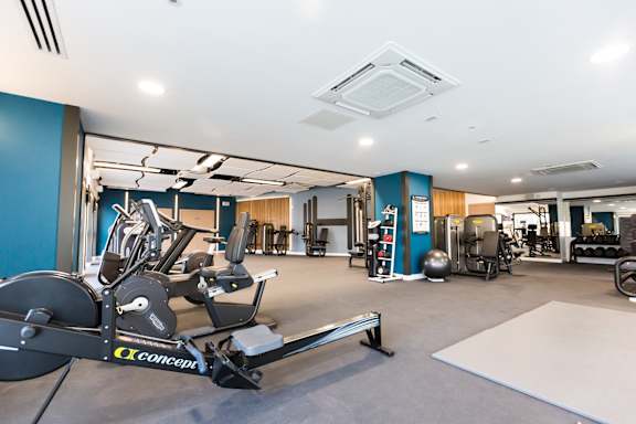 a gym with cardio equipment and weights in a building with blue walls