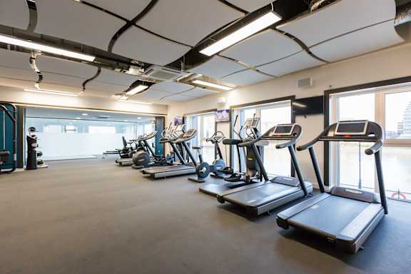 a workout room with cardio equipment and windows in a building