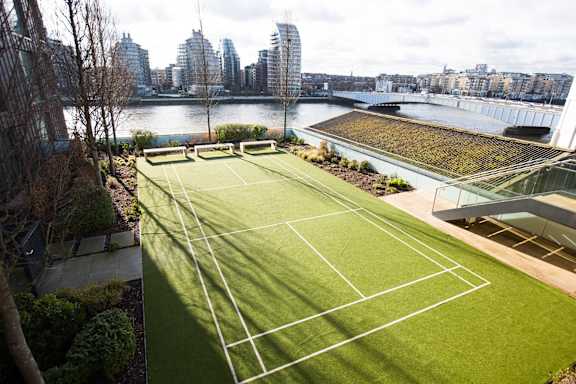 a tennis court on the roof of a building with a city in the background