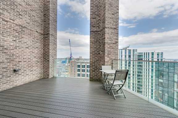 a balcony with a table and chairs and a view of the city