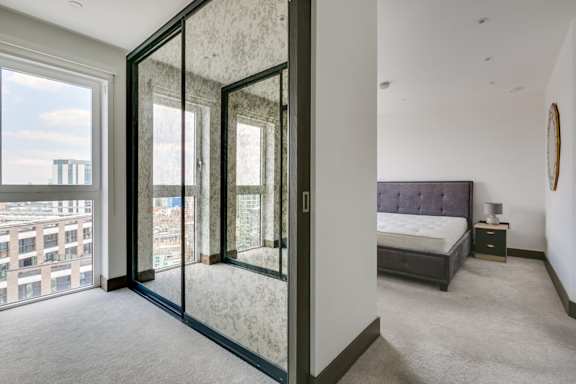 a bedroom with glass doors and a bed and a window