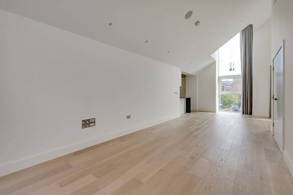a large white room with a wooden floor and a glass door