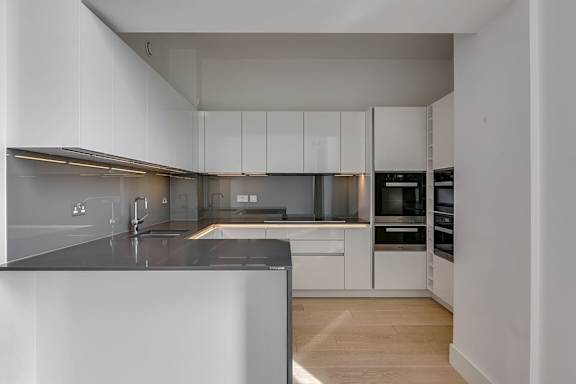 a kitchen with white cabinets and a black counter top