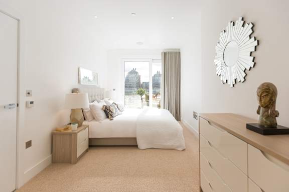 A bedroom with a bed, nightstand, and a large mirror on the wall.