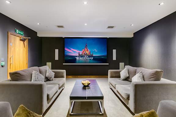 a living room with couches and a table with a movie screen on the wall