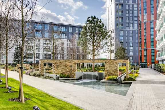 a courtyard with a water fountain and trees in front of tall buildings