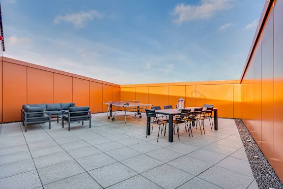 a rooftop terrace with tables and chairs and a pool