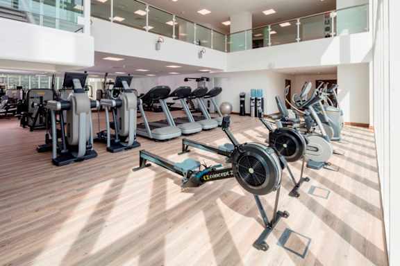 a state of the art gym with cardio equipment and weights on a wooden floor