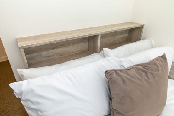 a bed with white sheets and a wooden headboard with pillows