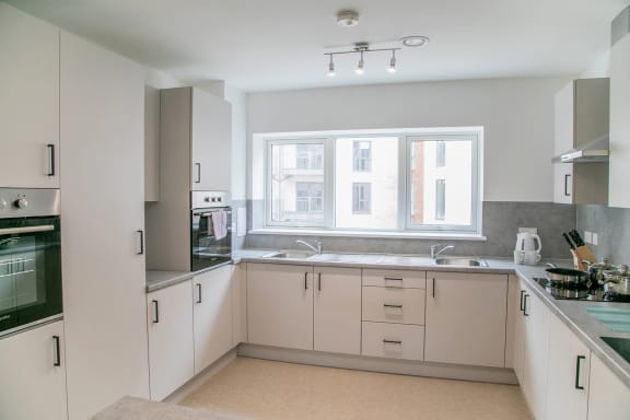 an empty kitchen with white cabinets and a window