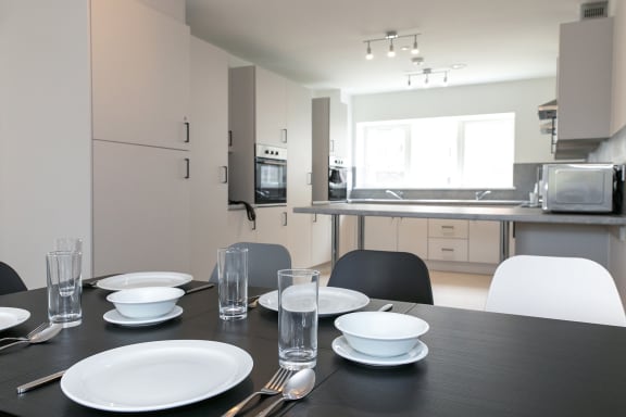 a dining table with plates and glasses in a kitchen