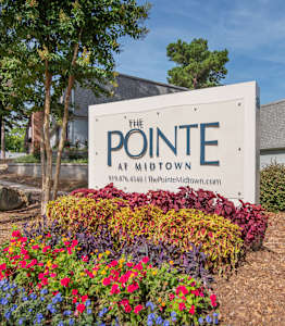 A sign for The Pointe at Midtown surrounded by flowers