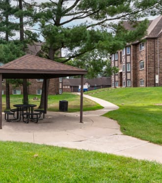 a picnic area with a gazebo in front of an apartment building